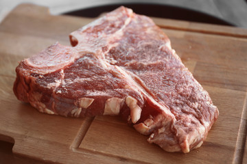 Fresh raw beefsteak on wooden board, closeup