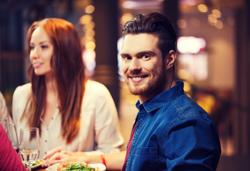 happy man with friends having dinner at restaurant