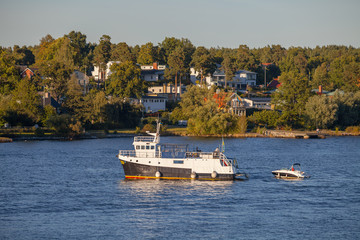 Obraz premium View on cruise boats and luxury cottages along Stockholm archipelago, Sweden. Summer sunset time.