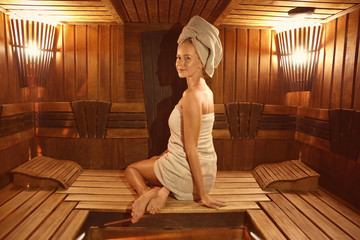 Young woman sitting on wooden bench in sauna
