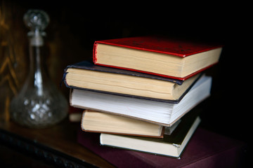 Paper books in a pile and a carafe of alcohol on the shelf intellectual. Education and intelligence are well-read people. Old gadgets from short stories and novels. The passing of time read.