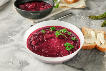 Delicious beet soup with parsley leaves on kitchen table