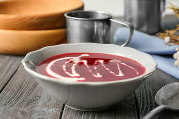Delicious beet soup with sour cream in bowl on kitchen table