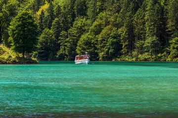Fototapeten Türkisfarbener See, weißes Schiff und grüner Wald. Sightseeing-Kreuzfahrt auf dem See © michalsanca