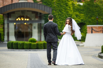 Fototapeta premium Look from behind at bride and groom walking on the backyard