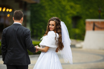 Naklejka premium Look from behind at bride and groom walking on the backyard