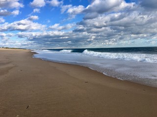 Fototapeta na wymiar Beautiful empty sand beach with surfer waves and a blue sky with white clouds in Charlestown, Rhode Island (United States of America)