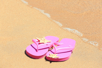 Fototapeta na wymiar Colorful flip-flops and starfish on sand at sea shore. Vacation concept