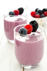 Healthy berry smoothie in glass on white wooden table
