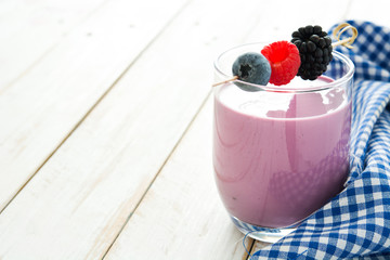 Healthy berry smoothie in glass on white wooden table
