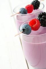 Healthy berry smoothie in glass on white wooden table

