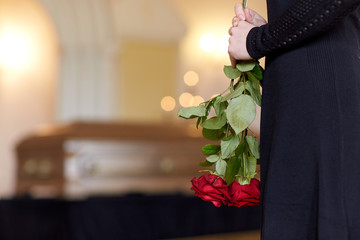 close up of woman with roses and coffin at funeral