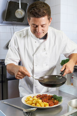 Chef Adding Sauce To Dish In Restaurant Kitchen