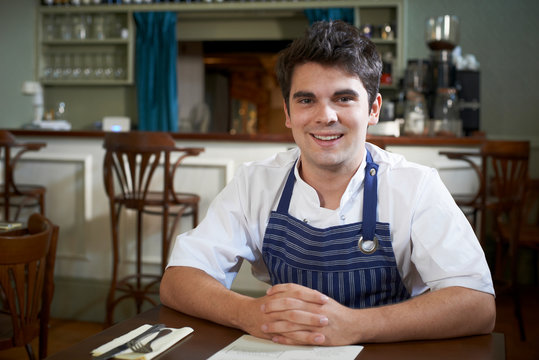 Portrait Of Chef Sitting At Table In Restaurant