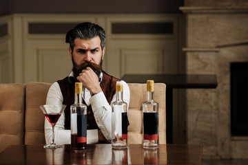 Man sitting at table with three bottles and glass