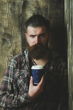 Brutal bearded hipster holding plastic coffee cup