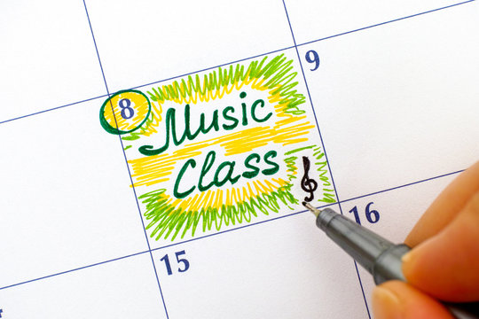 Person fingers with pen writing reminder Music Class in calendar.