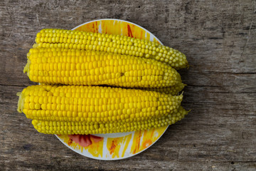 Boiled corn on plate on rustic wooden table
