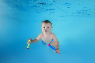 little boy with toy dives underwater in the swimming pool