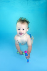 Fototapeta premium little boy with toy dives underwater in the swimming pool