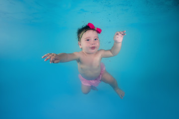 Fototapeta na wymiar Little girl swims under water