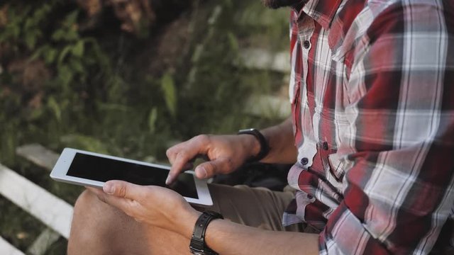 young hipster red bearded man at the park enjoing good weather, red shirt on green background, student doing homework after university lessons