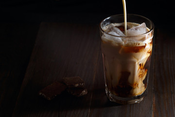 Iced coffee in a tall glass with cream poured over
