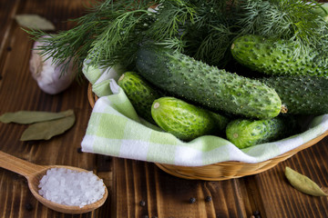 Cucumbers and dill in the wicker basket on the wooden background