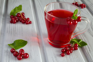 Red currant compote in the glass cup on the grey wooden background