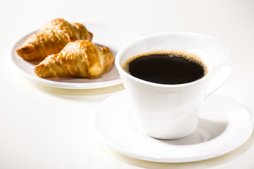 White cup with coffee and croissants