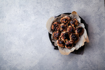 Cinnabon buns with chocolate cream on gray concrete background. Rustic styling; copy space