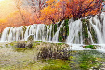 Autumn view of the waterfall with pure water at sunrise time.