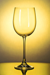 Beautiful empty wine glass toned in yellow, close-up shot against the light