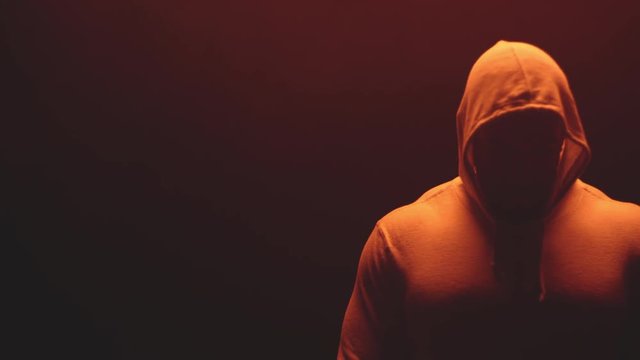 Muscular black man standing on a foggy dark red background, wearing a hoodie 
