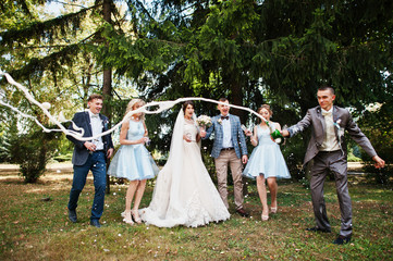 Stunning wedding couple with bridesmaids and groomsmen drinking champagne in the park on a perfect sunny day.