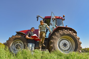 Getreideanbau - Landwirte beraten sich vor einem Traktor auf einem Getreidefeld © Countrypixel