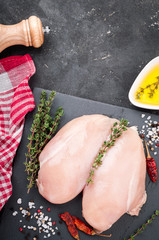 Chicken breast with spices, herbs, olive oil on dark background, top view. Raw meat chicken for cooking. Delicious balanced food concept. Copy space