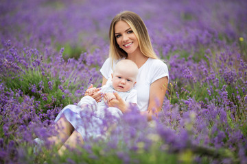 Happy mother and her little baby boy having fun in a lavender field