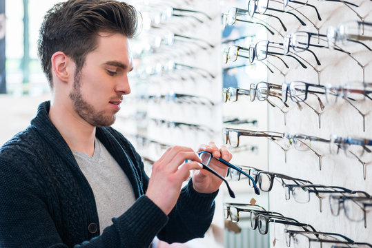 Man in front of shelf with glasses in optician shop