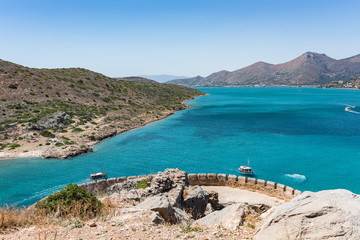 Top of Spinalonga island. View to blue aegian sea with boats, Kalydon island and Mirabello coast.