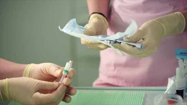 Dentist opening pack of sterile glass syringe. Preparing of work plase. Dentist work with assistant.