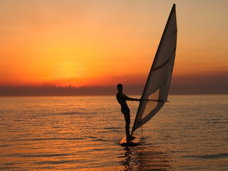 windsurfer silhouette against a sunset background - natural sky