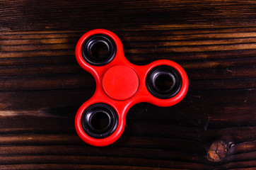 Red fidget spinner on wooden desk. Top view