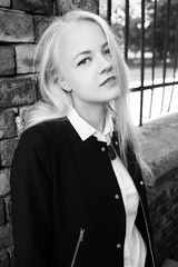 Obraz premium blond beautiful girl near old bricks wall looking at camera, monochrome