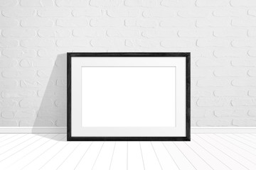 Black wooden photo frame on the floor near white bricks wall