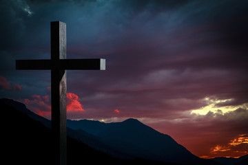 Jesus Christ cross on a background with dramatic sky and colorful, red, orange, purple sunset on...
