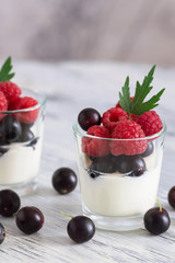 Yogurt with raspberries and currants in a small glass.