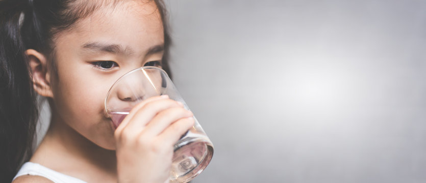 Child Drinking Water From Glass. Happy Little Girl At Home