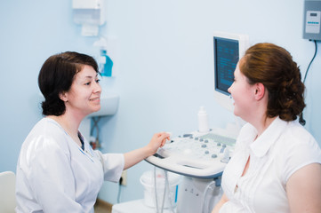 Satisfied pregnant woman having doctor's appointment with ultrasound diagnostics