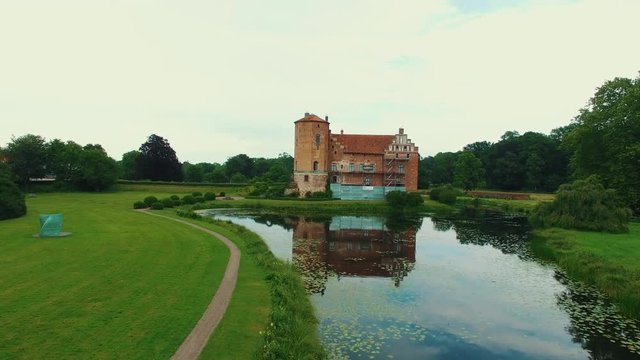 Aerial flight towards castle in Southern Sweden. View of fortress palace and canal